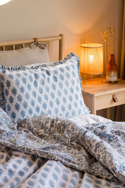 Bedroom with a round window, lamp, and decorative pillows on a bed.