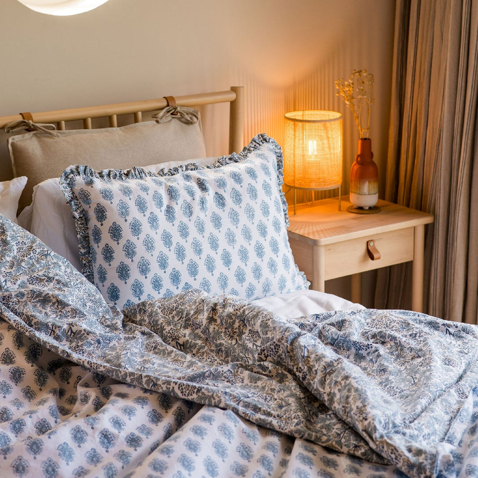 Bedroom with a round window, lamp, and decorative pillows on a bed.